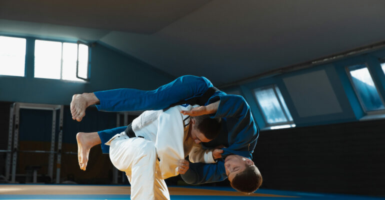 Two young judo fighters in kimono training martial arts in the gym with expression, in action and motion